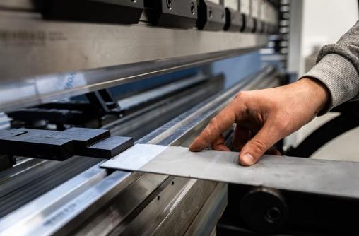 Operator loading sheet metal into a press brake before bending
